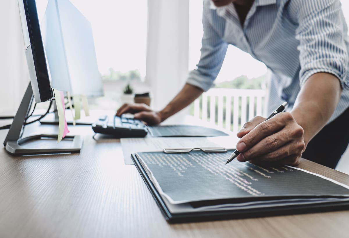 Professional reviewing documents and records at a computer