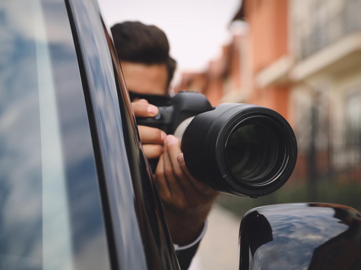 Investigator taking a discreet photograph from beside a vehicle